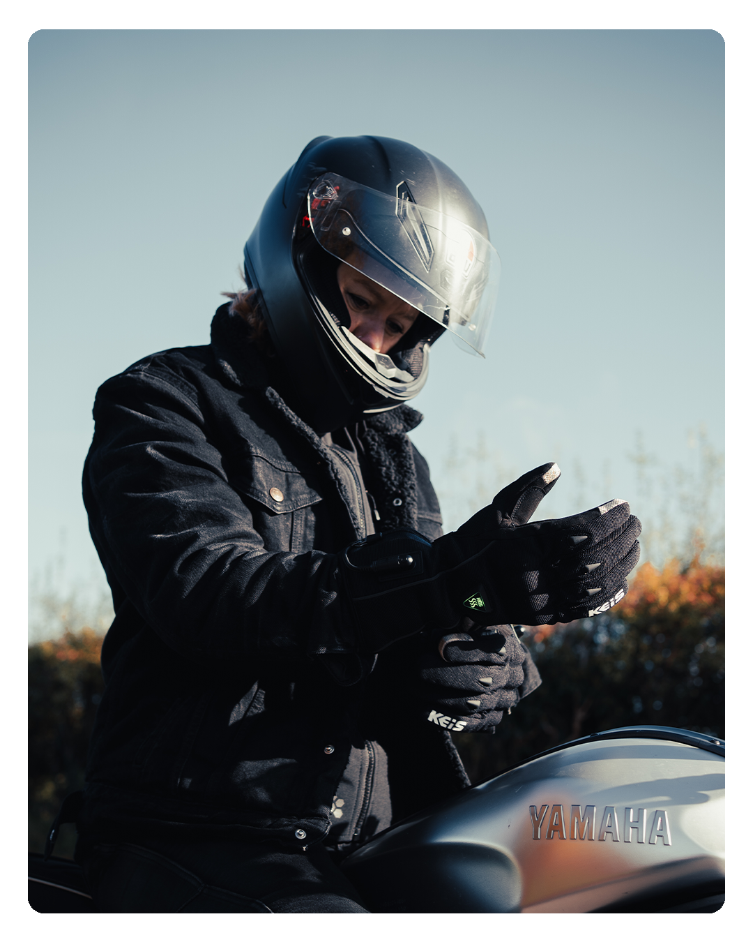 A rider pressing the heat control button on the heated glove's cuff, the setting light showing green.