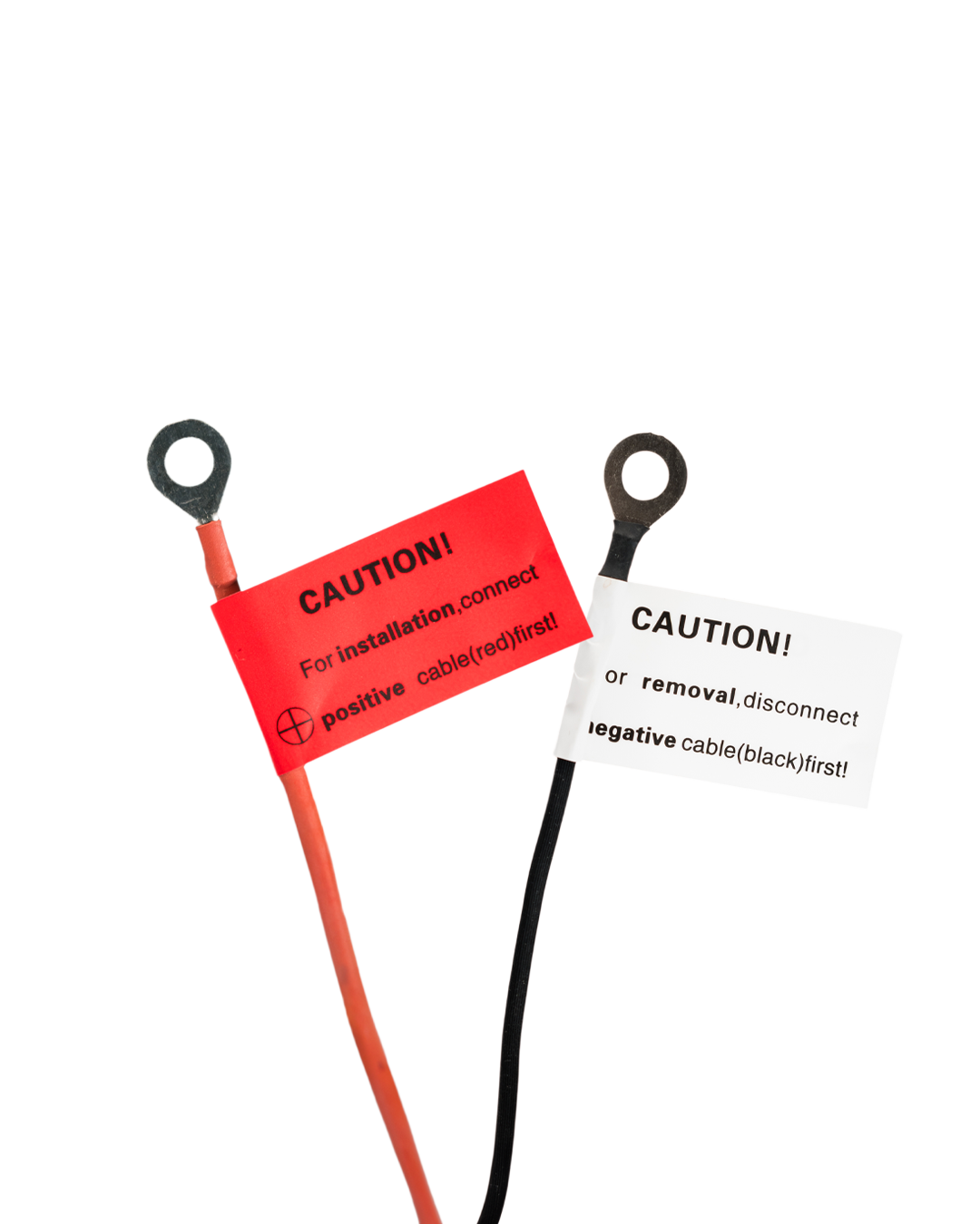 Close-up of the supply lead's two ring terminals, each with a printed caution tag about connection order.